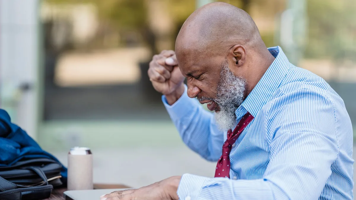 A bald man with a beard looking frustrated at his laptop