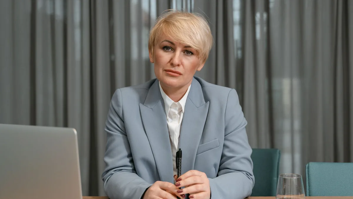 A confident businesswoman in a blue suit sits at her des