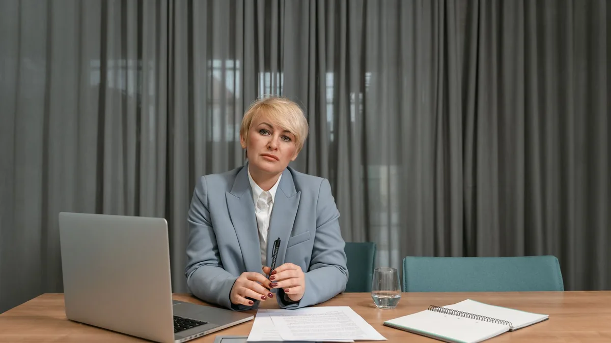 A confident businesswoman with short hair sits at a desk