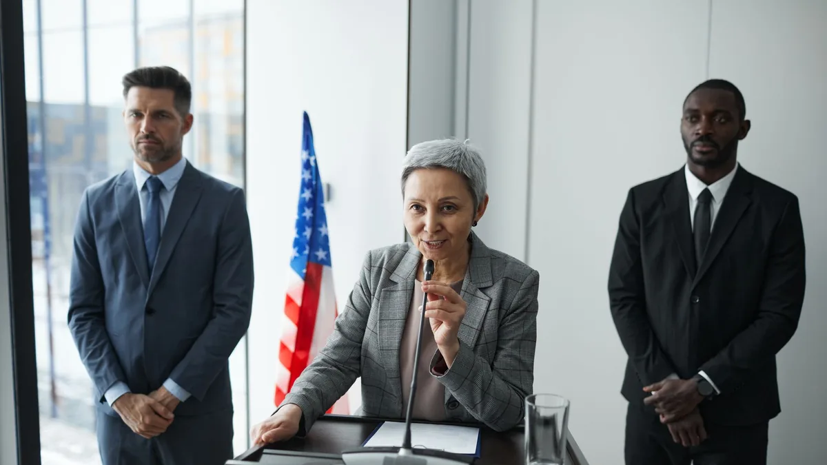 A female politician delivers a speech with bodyguards an
