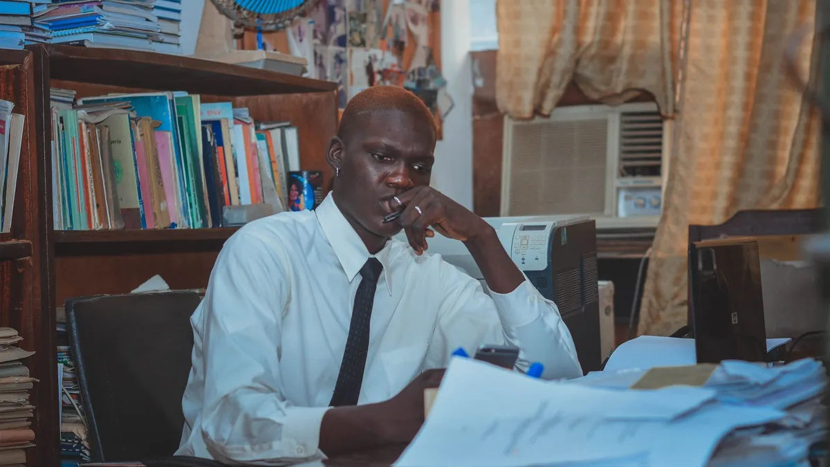 A focused adult man working at a cluttered office desk s