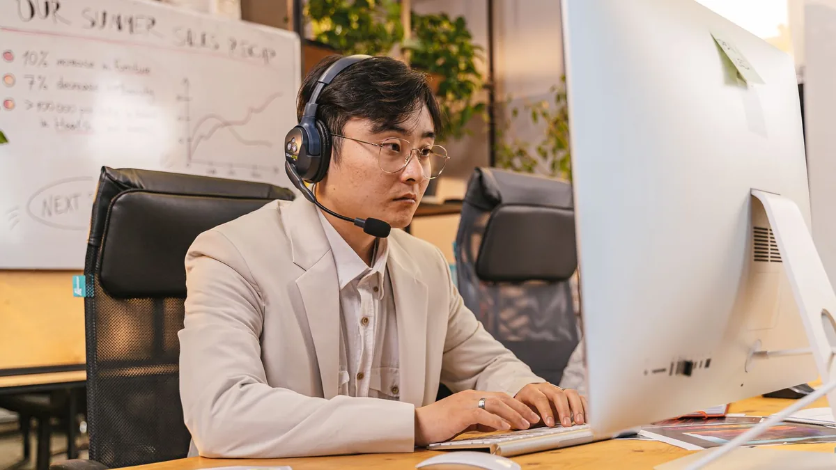 A focused man in a suit uses a desktop computer in a mod