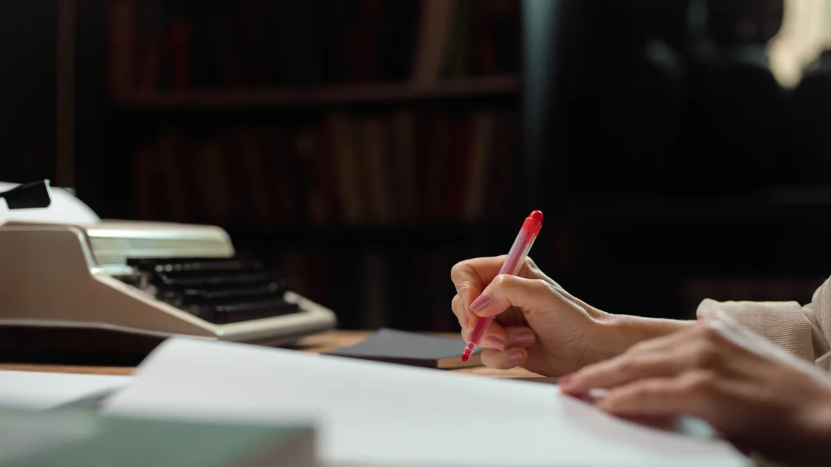 A hand writing with a pen in a cozy library setting with