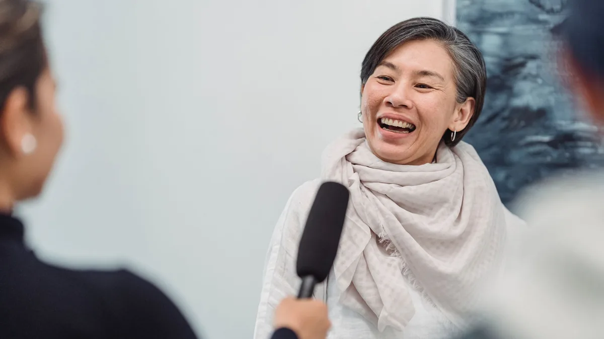 A joyful woman being interviewed with a microphone smili
