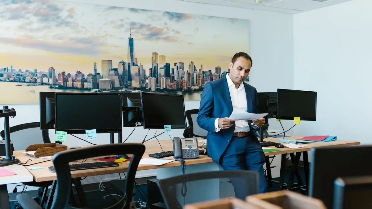 A man in a suit reviews documents in a modern office set