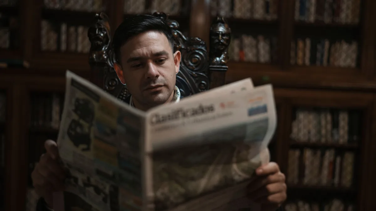 A man in an ornate chair reads a newspaper in a sophisti