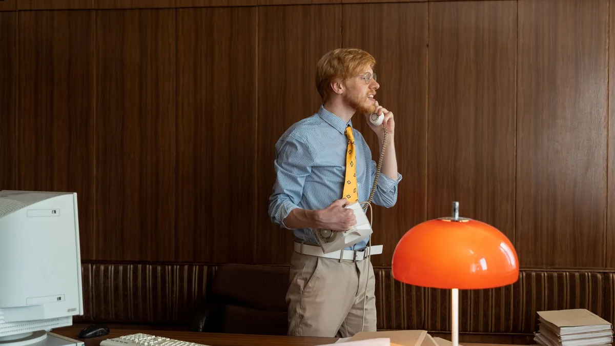A man in retro attire talking on a corded phone in a vin