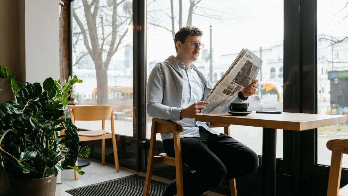 A man reading a newspaper in a cozy coffee shop setting