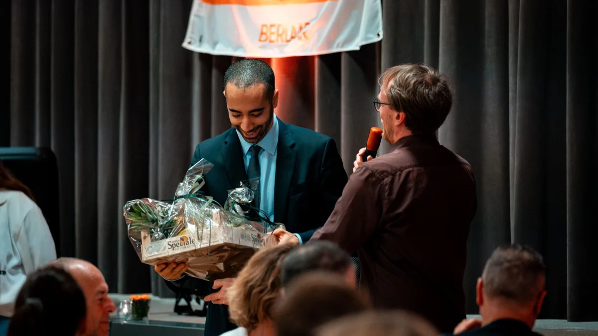 A man receives a gift basket during an award ceremony in