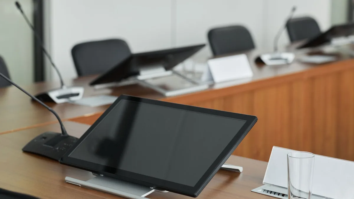 A modern conference room setup featuring digital monitor
