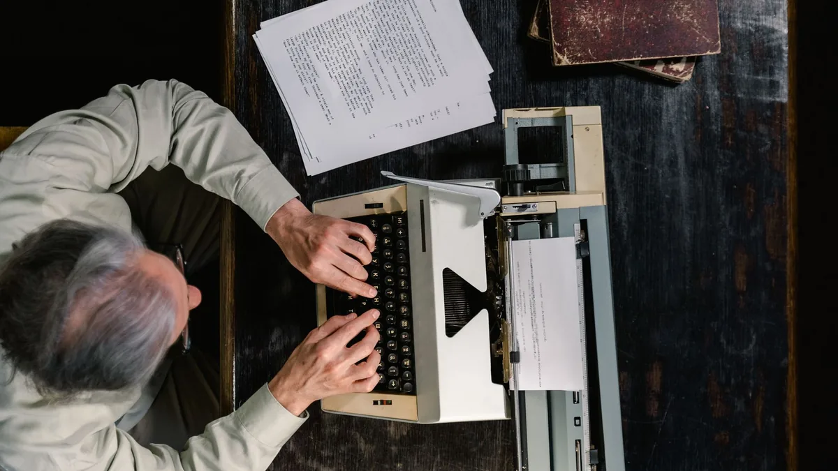 A person typing on a vintage typewriter with scattered p