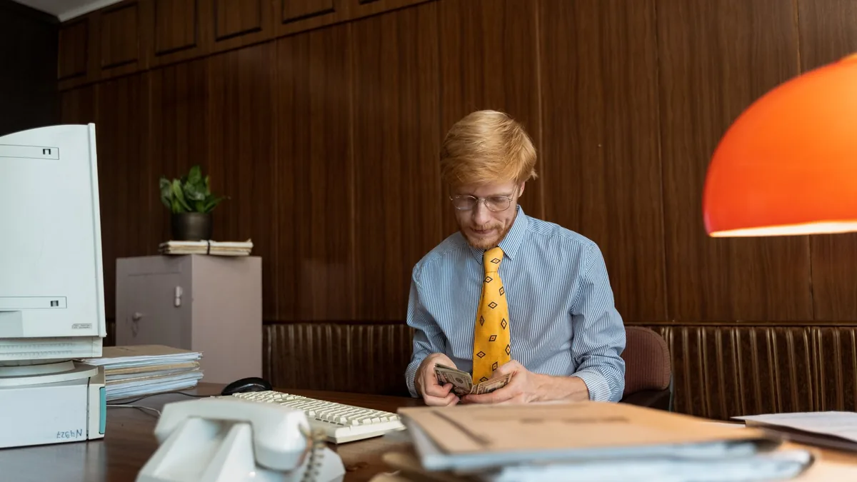 A professional counting cash at a retro office desk feat