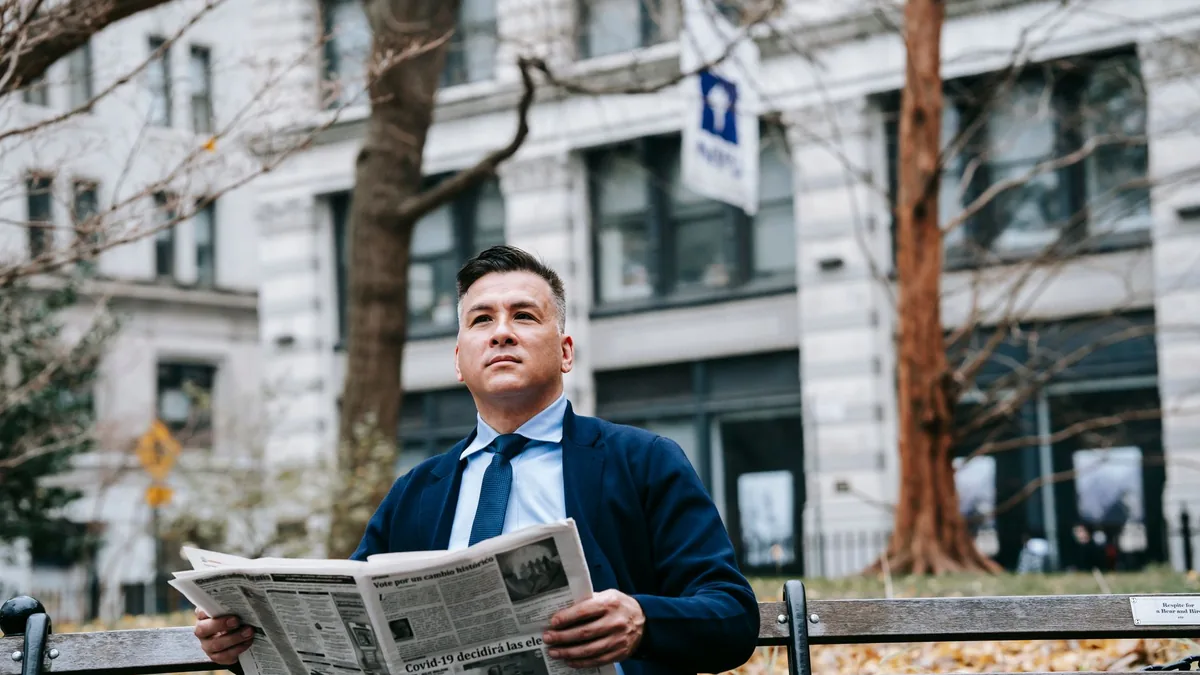 A professional man in formal attire reading a newspaper