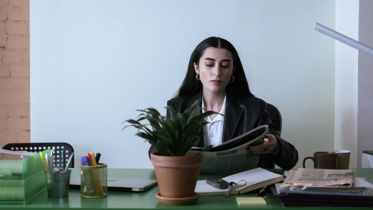 A professional woman reading a newspaper at her desk in