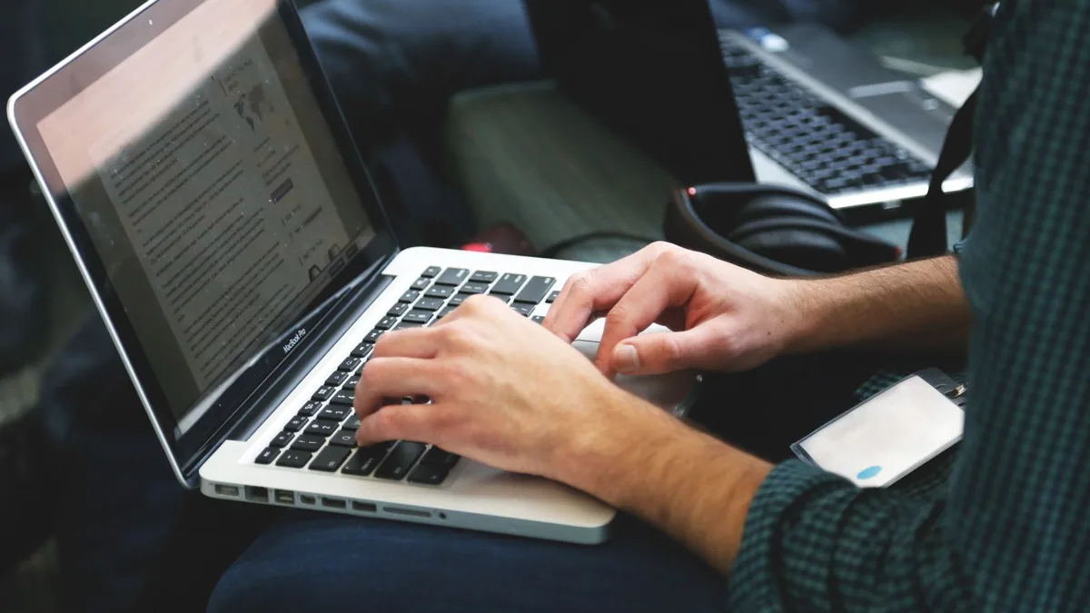 A programmer typing on a laptop in an indoor setting sho 7114