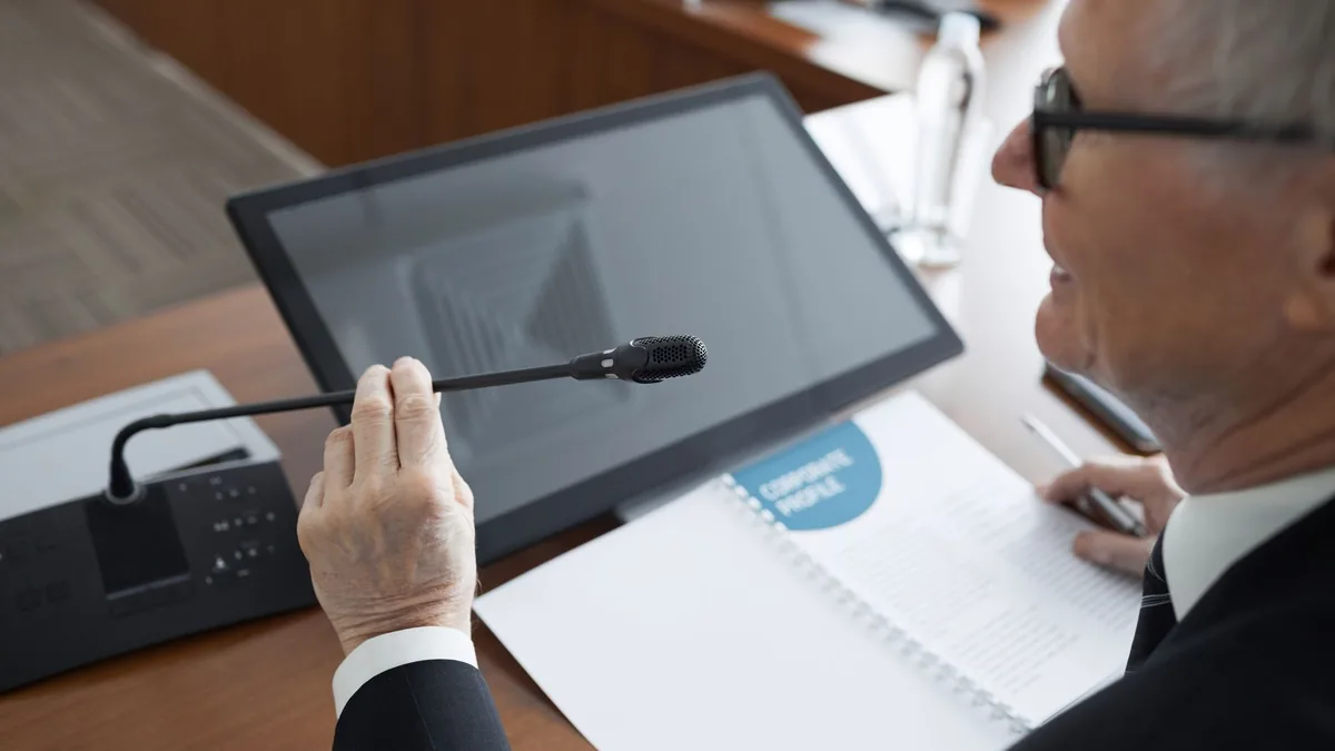 A senior businessman using a microphone during a confere