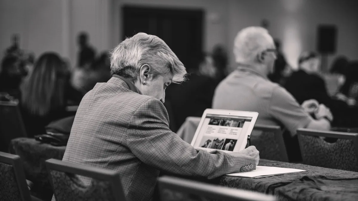 A senior journalist takes notes during a conference engr