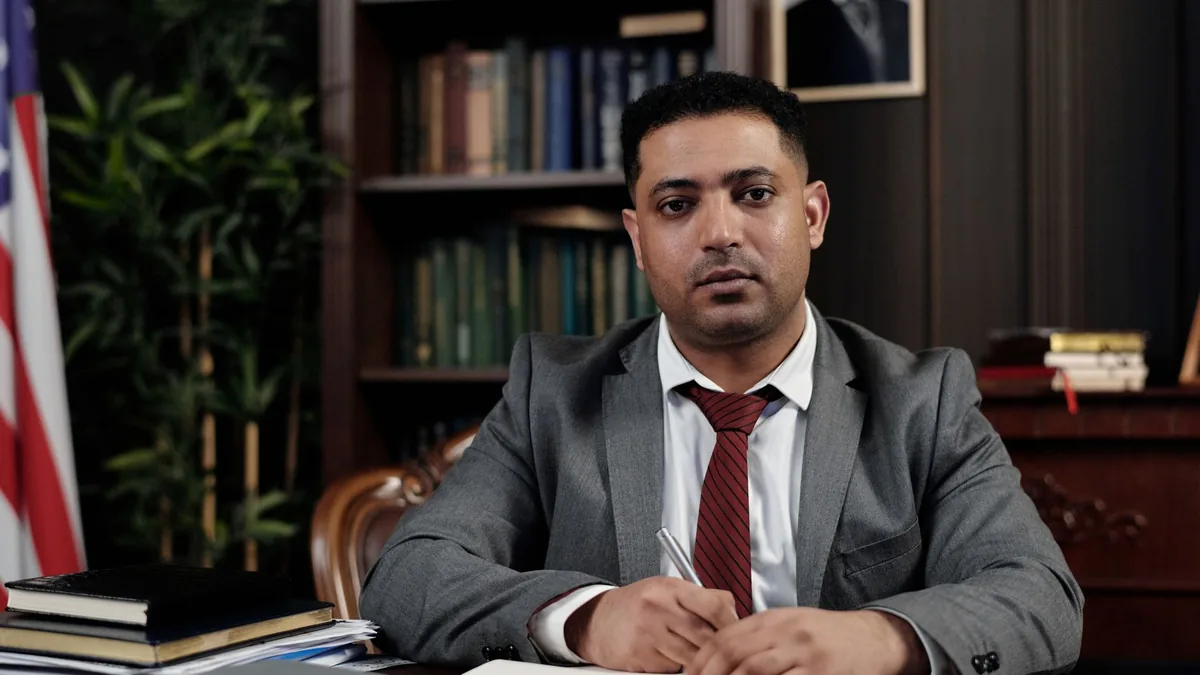 A serious businessman in a suit writing at his desk in a