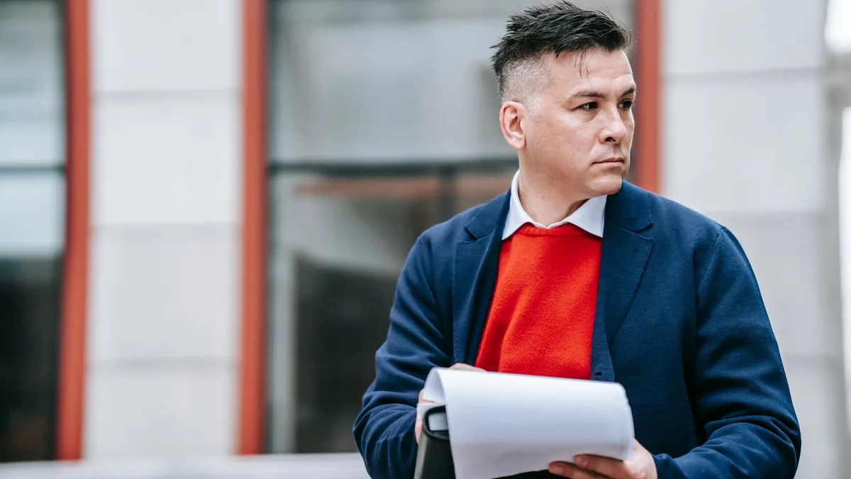 A serious man holding papers dressed professionally in a
