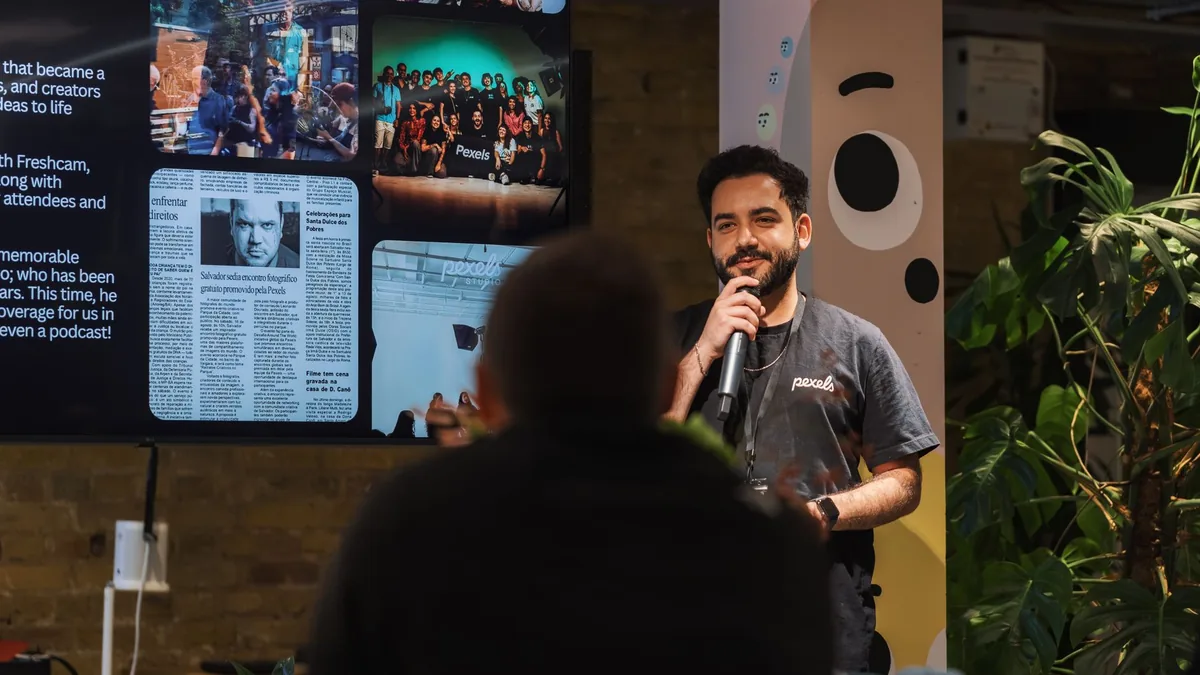 A speaker holding a microphone addresses an audience ind