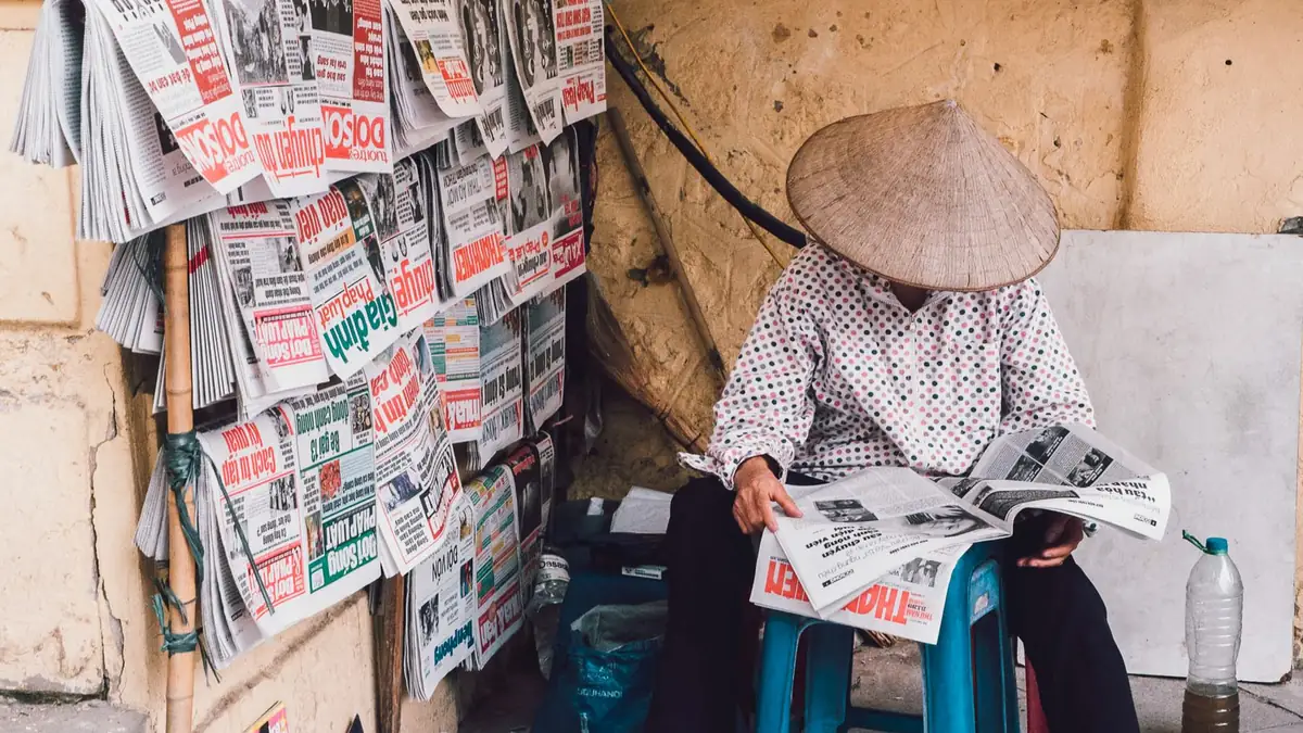 A street vendor in hanoi reads newspapers showcasing dai
