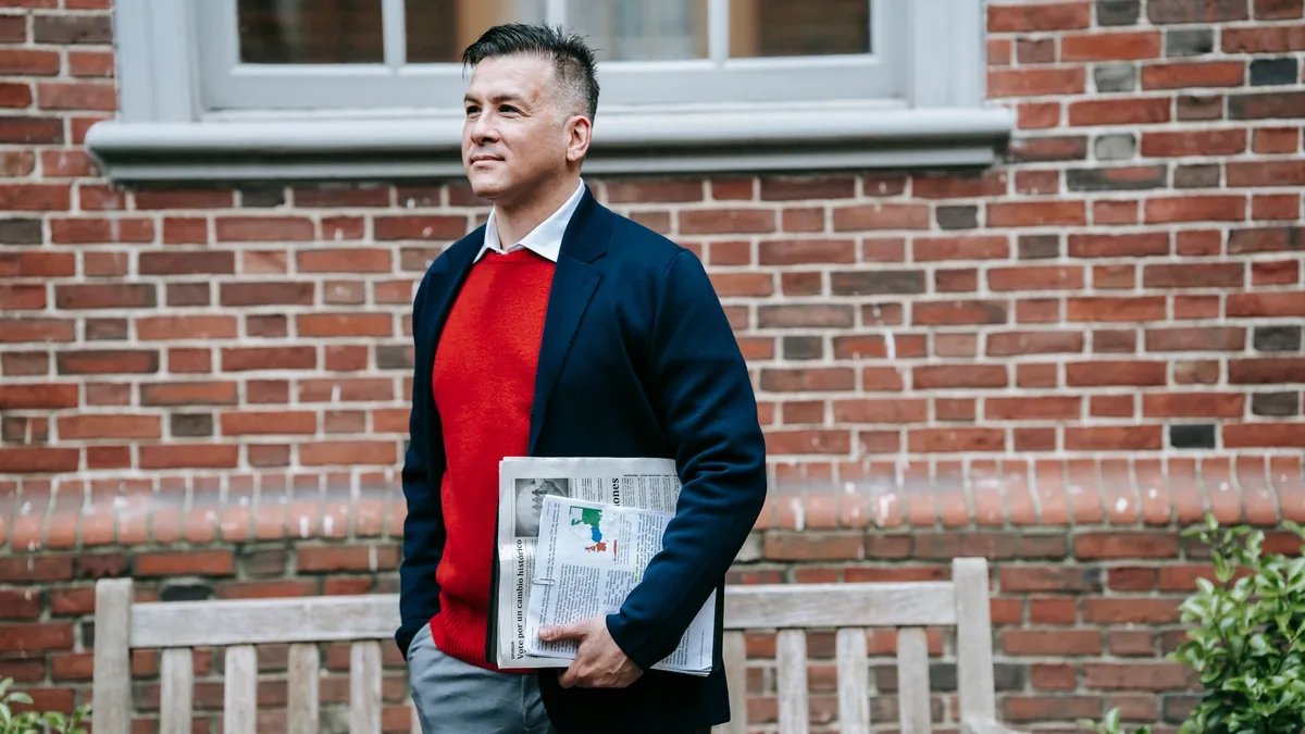 A stylish man in a smart outfit holding a newspaper outd