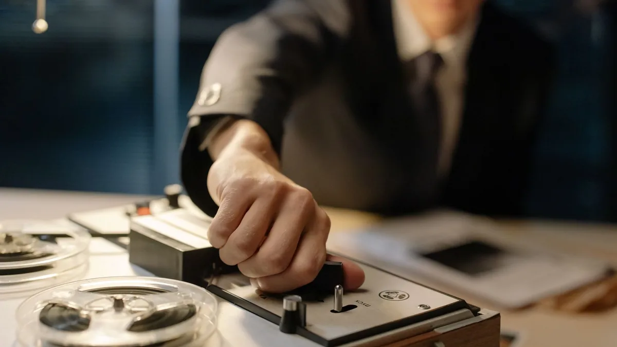 A suited man operates a retro tape recorder evoking a cl