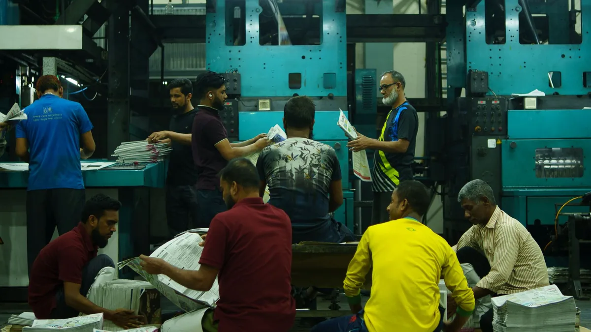 A team of workers sorting newspapers in an industrial pr