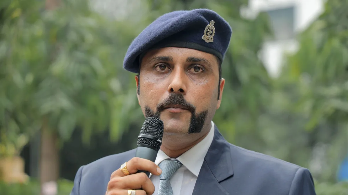 A uniformed officer with a microphone outdoors wearing a