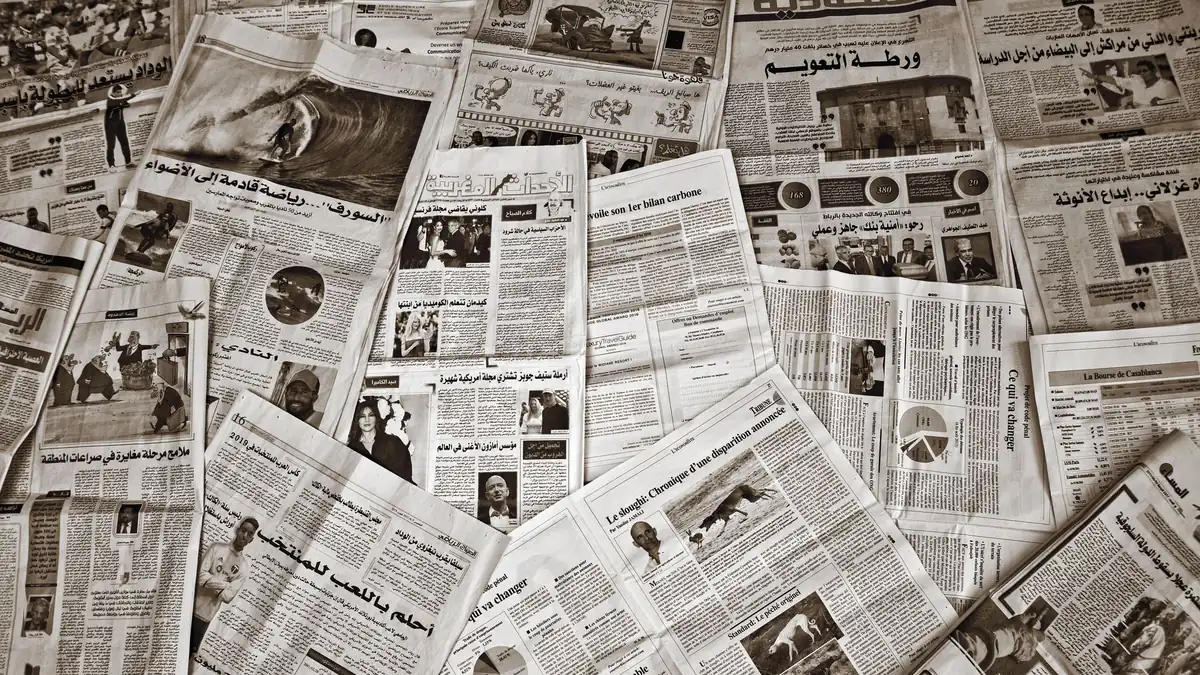 A variety of arabic and french newspapers spread out sho