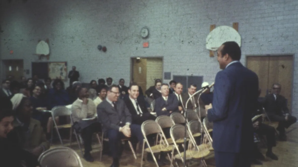 A vintage community meeting in a gymnasium with diverse