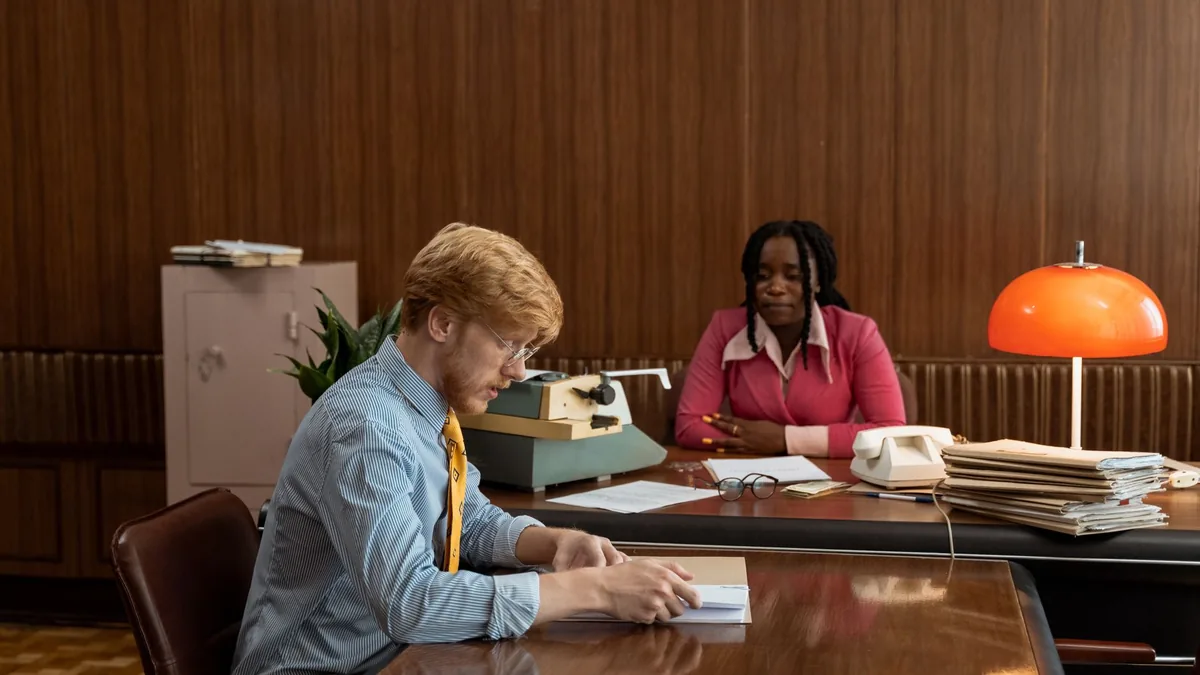 A vintage office setting with two people engaged reflect