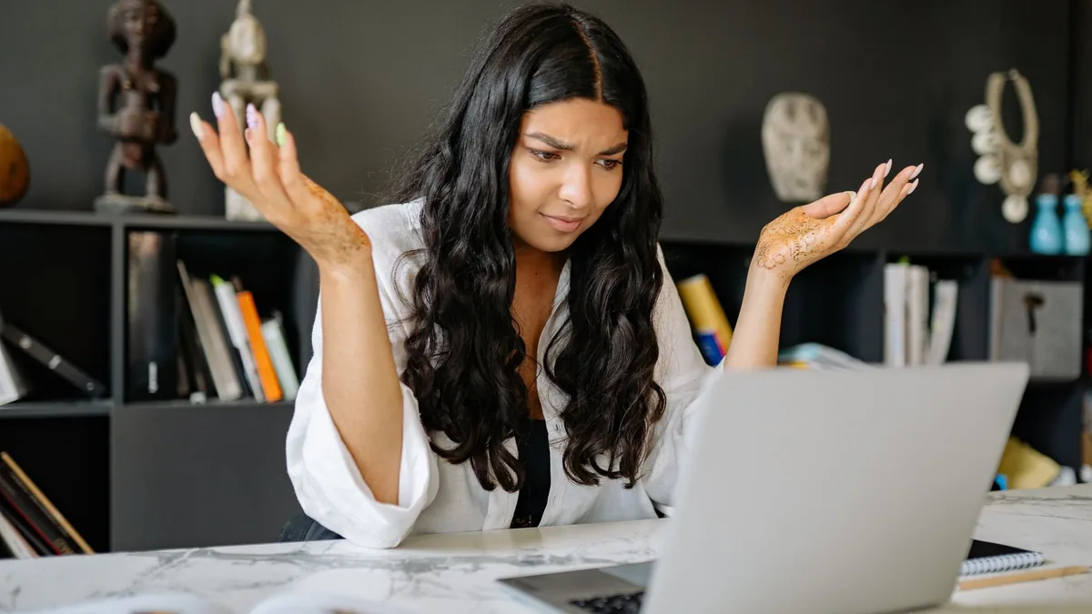 A woman at an office desk looks frustrated while working