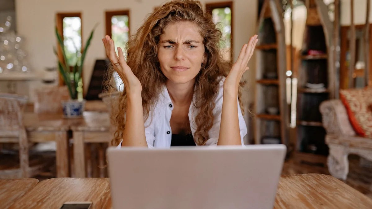 A woman frustrated with her laptop while working remotel