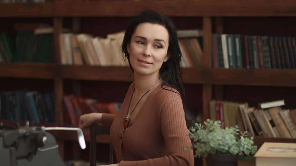 A woman in a brown outfit sitting in a cozy library sett