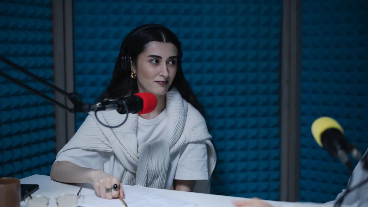 A woman in a podcast studio with microphones and headpho