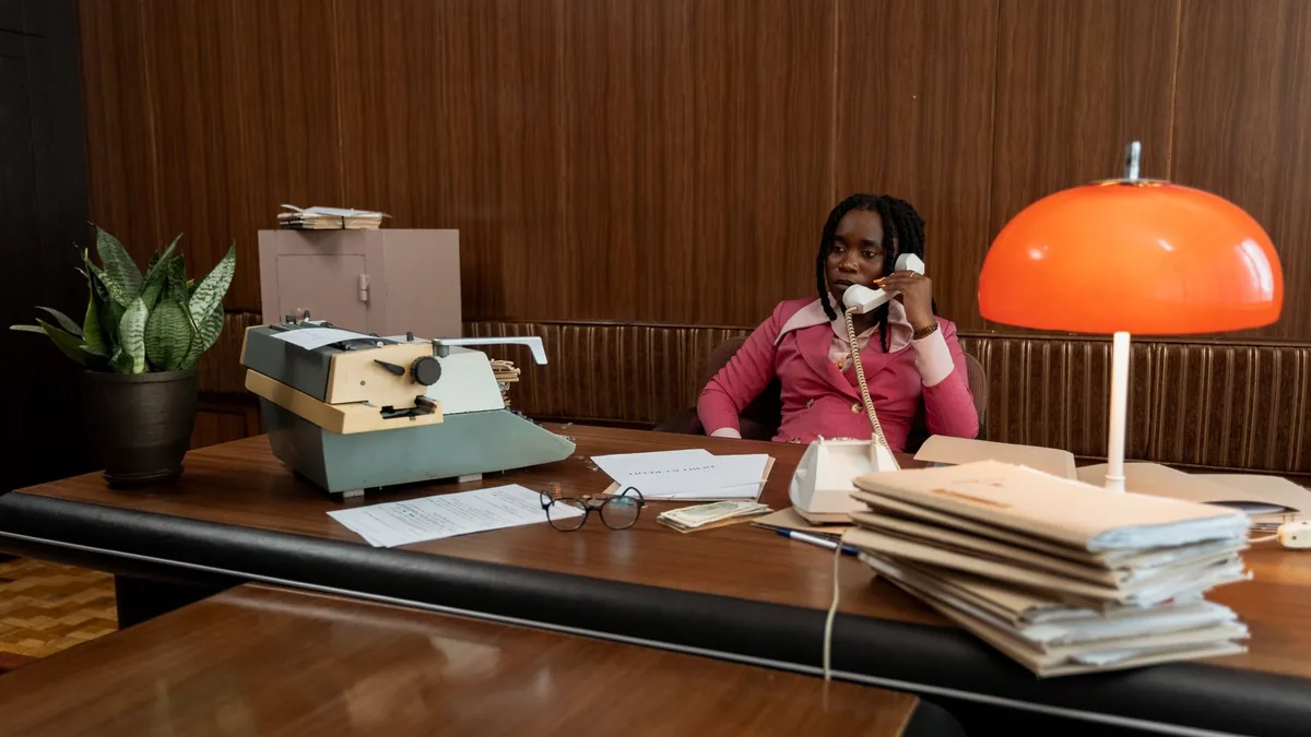 A woman in a retro office setting making a phone call wi