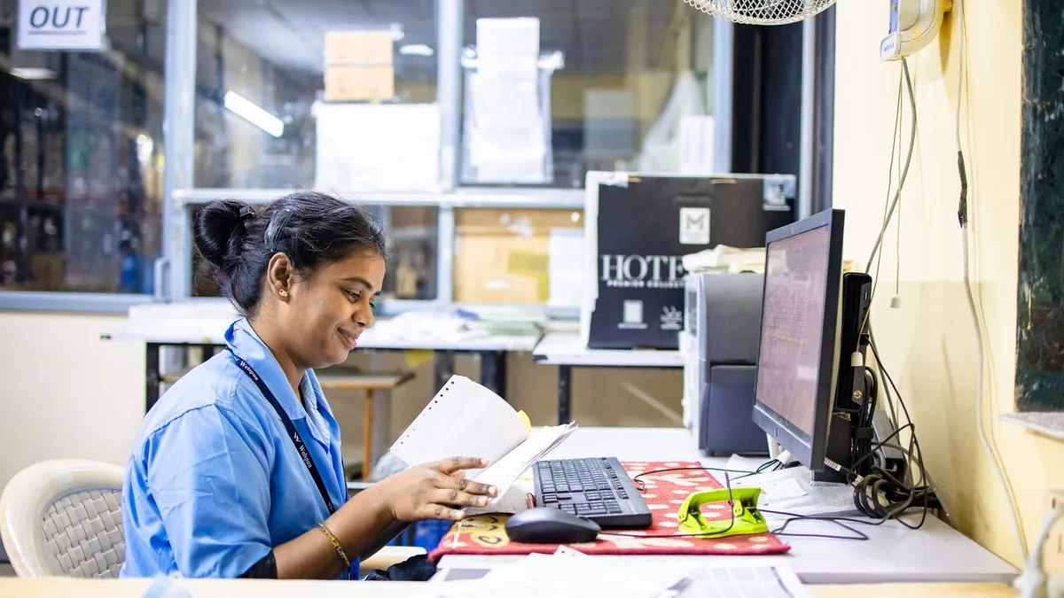 A woman in an office setting reading paperwork at her de