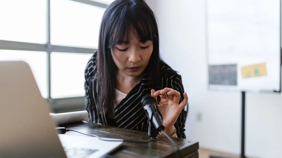 A woman in an office setting testing a microphone while