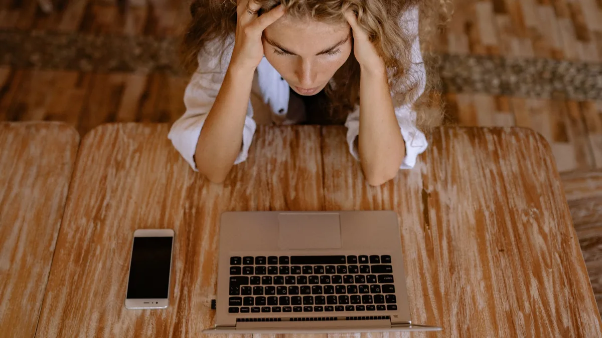 A woman looking stressed while working on a laptop from