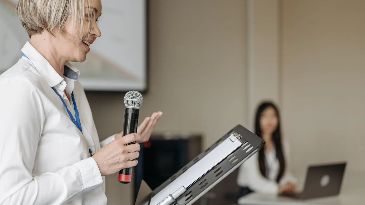 A woman presenting with a microphone at a professional s
