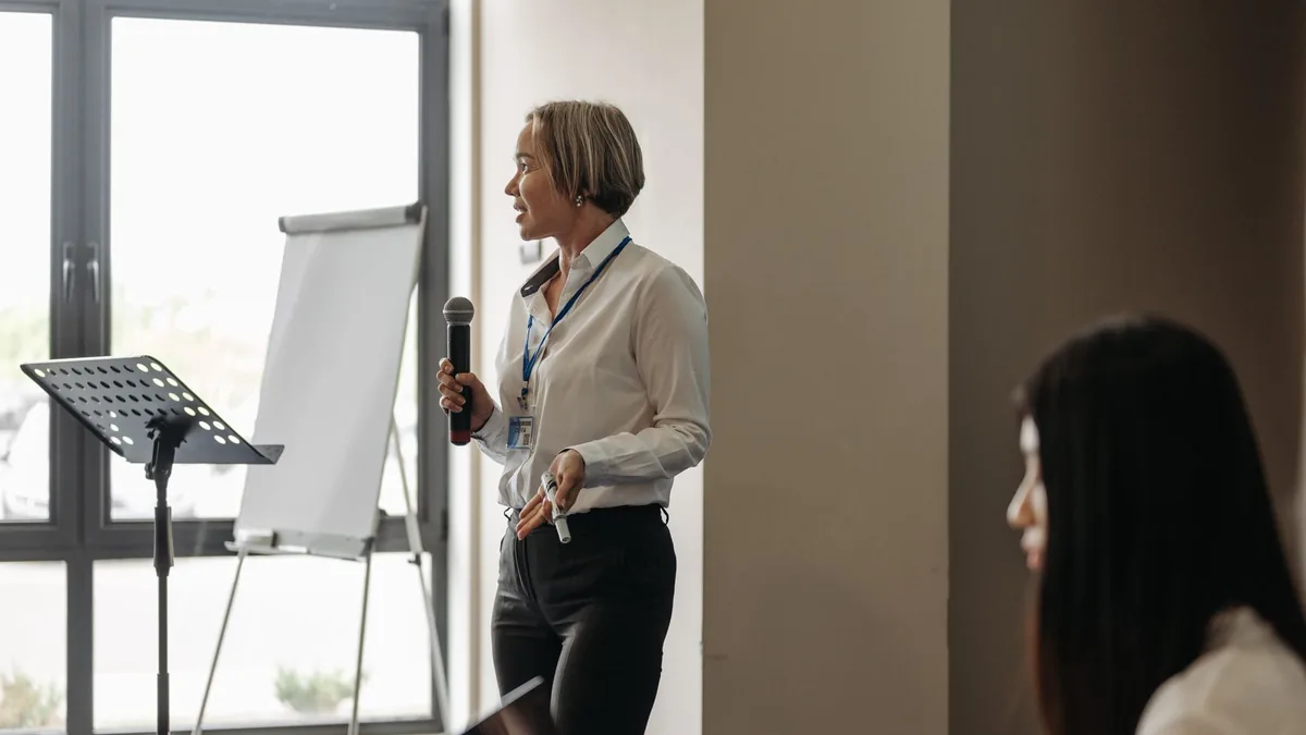 A woman presenting with microphone and flipchart in a co