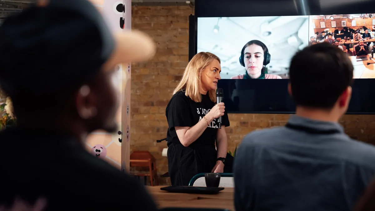 A woman presents to an audience during a hybrid conferen
