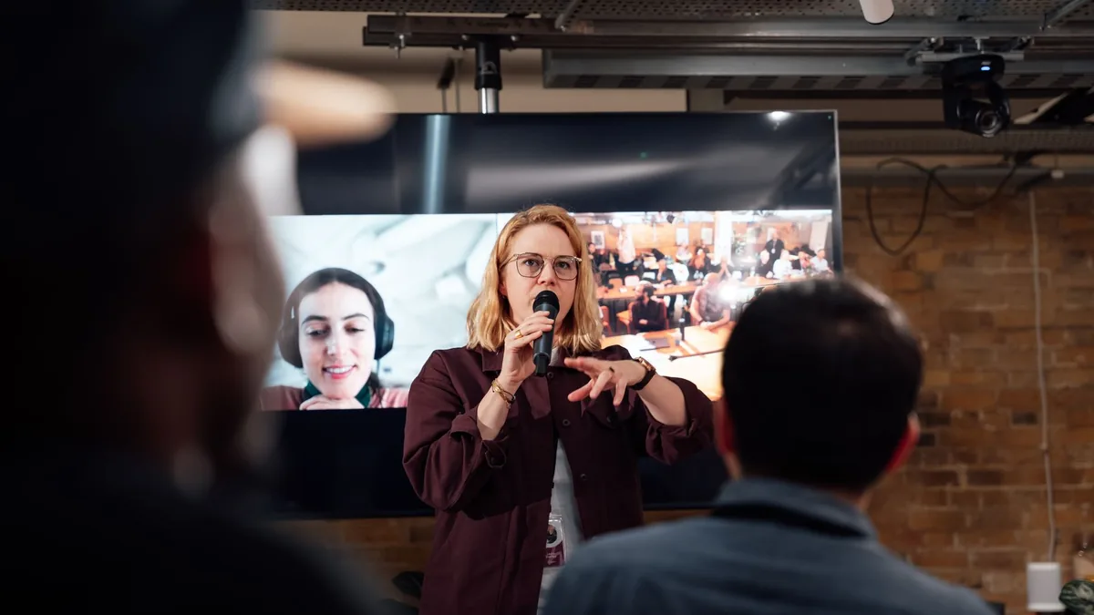 A woman presents using a microphone in a london event sp