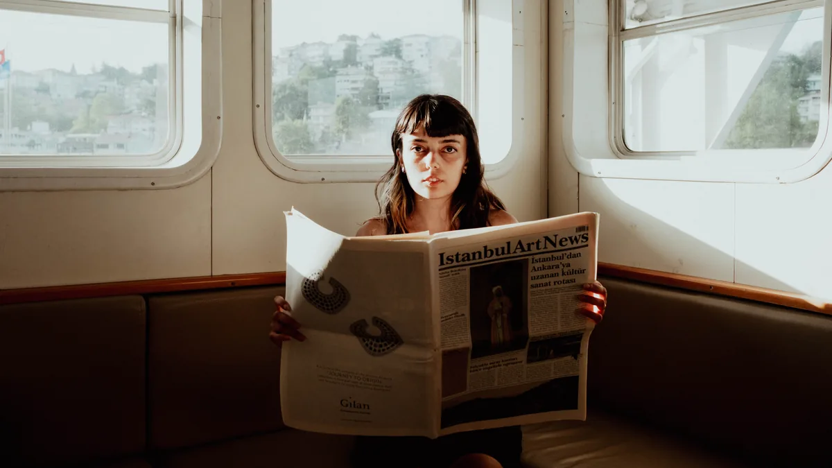 A woman reads a newspaper inside a ferry in istanbul t r