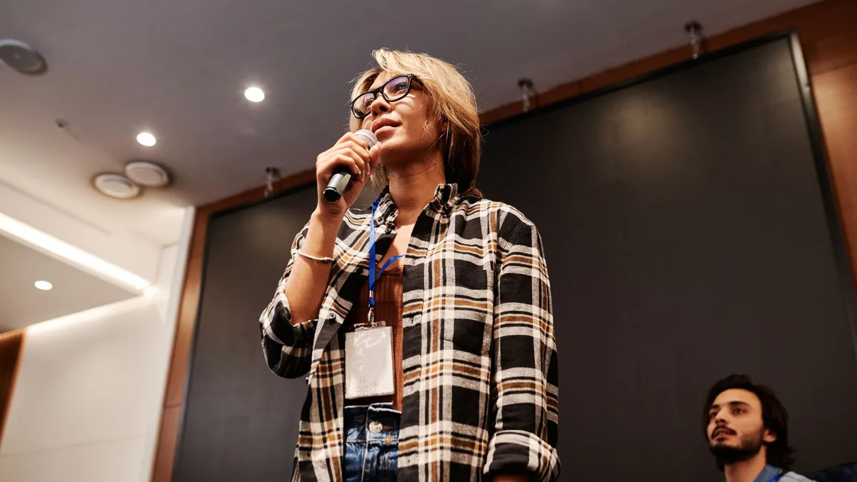 A woman speaks confidently with a microphone during an i
