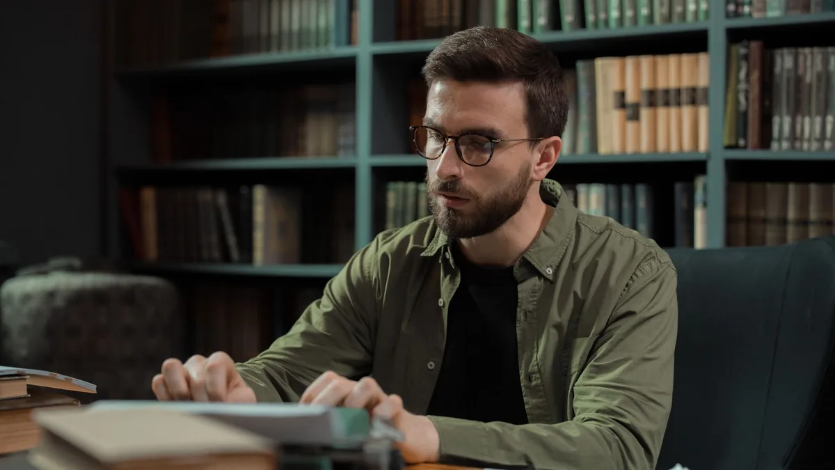 A young man with glasses typing on a vintage typewriter