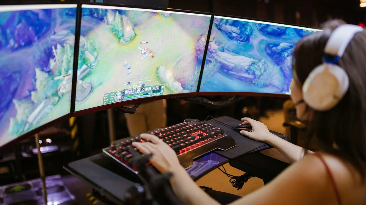 A young woman intently gaming on a multi screen setup sh