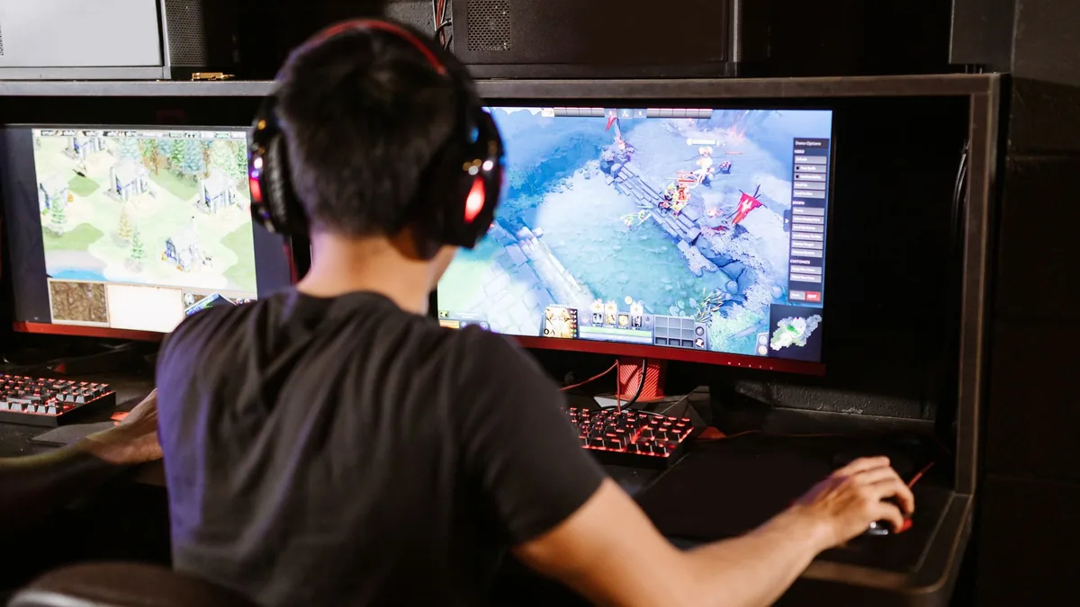 Adult male gamer immersed in pc gaming on dual monitors