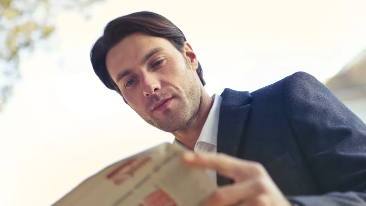 Adult man in formal attire reading a newspaper outdoors